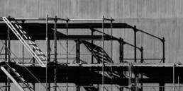black and white photo of scaffolding by a building wall